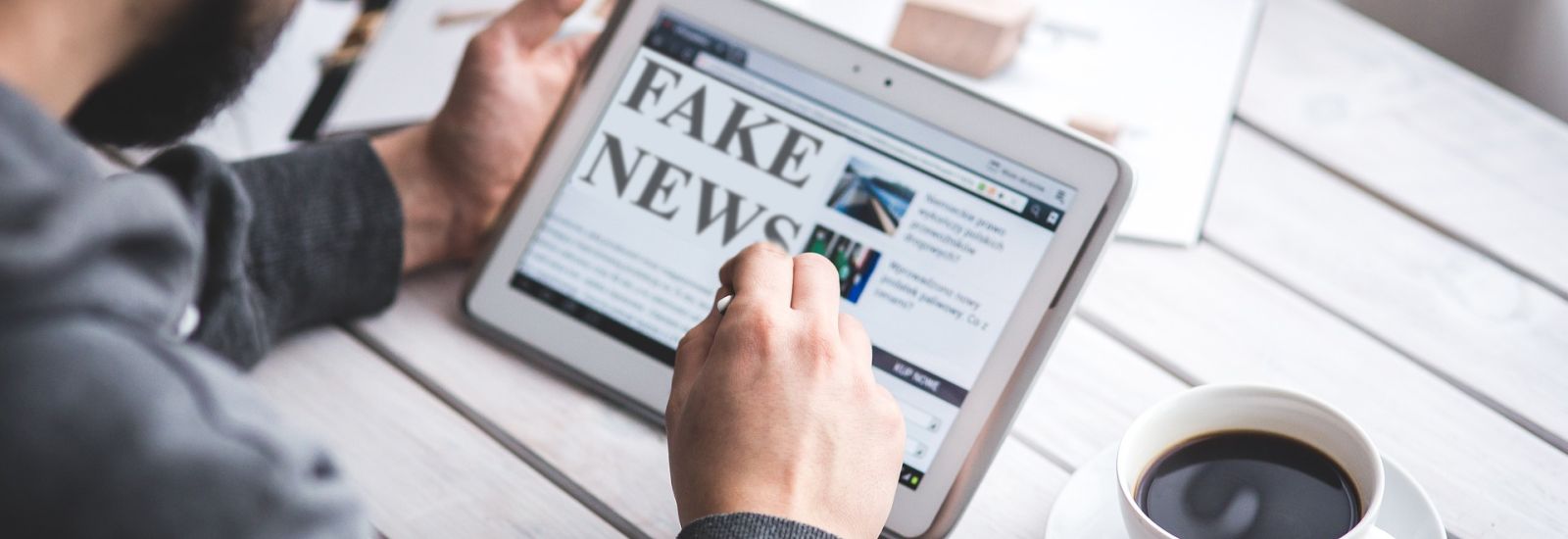 man working o ipad with words fake news on screen