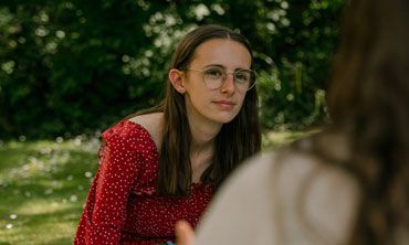 A student sitting outside, listening to a tutor