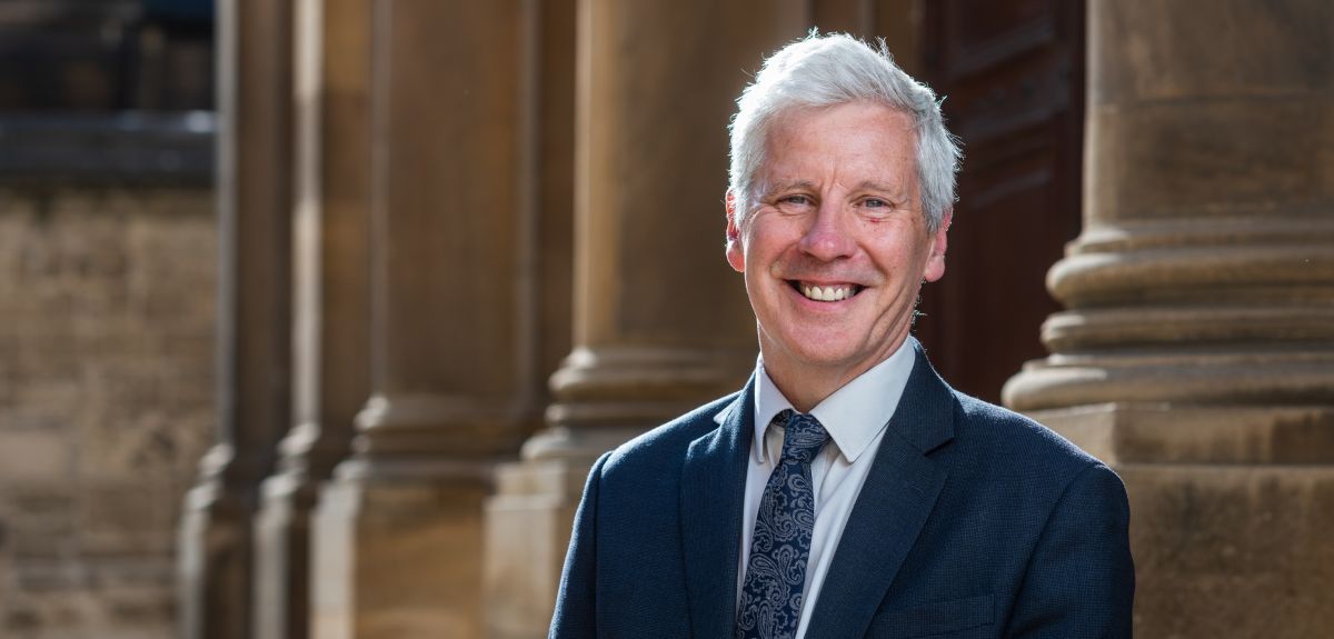 Martin Williams smiles while standing outside an Oxford building